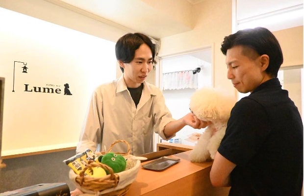 お迎えの時間になり、飼い主さんがワンちゃんを抱えている写真